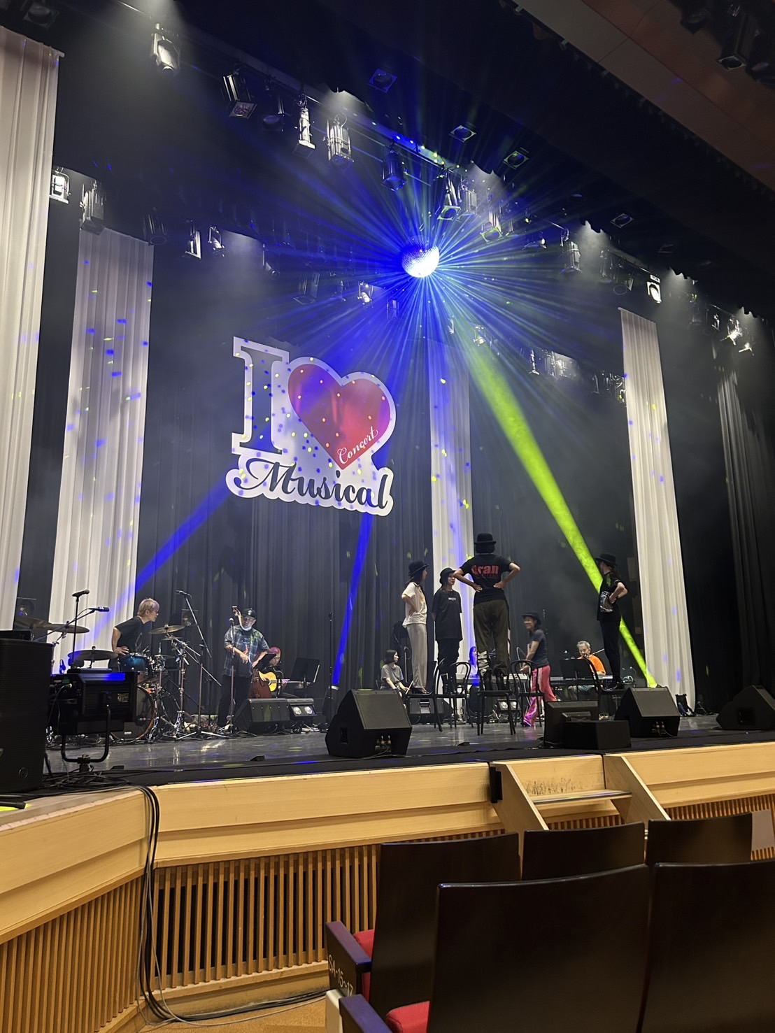 I Love Musical コンサートのステージでリハーサルを行う出演者とバンドメンバー。照明演出とミラーボールが輝く華やかな舞台